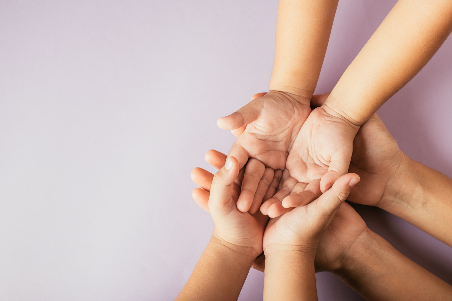 Outstretched adult hands support pairs of children’s hands in their palms