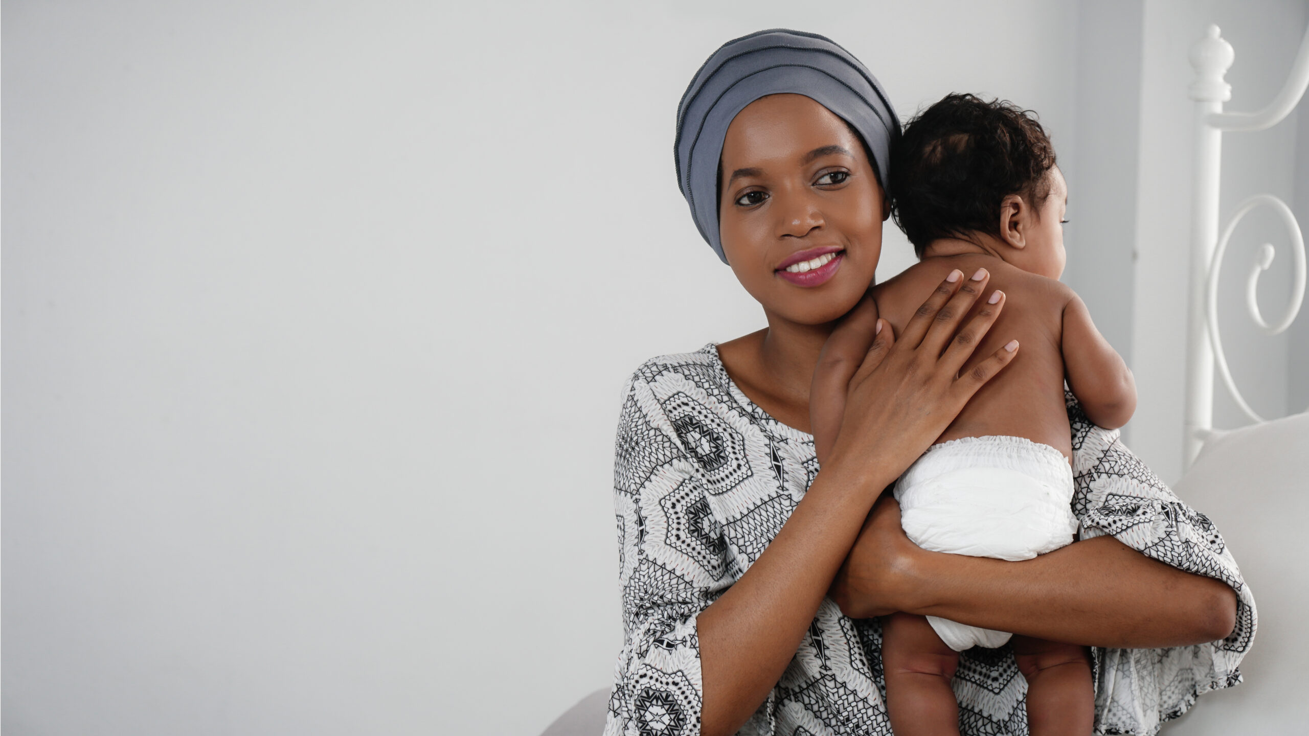 Black mother holding her baby to her shoulder and smiling